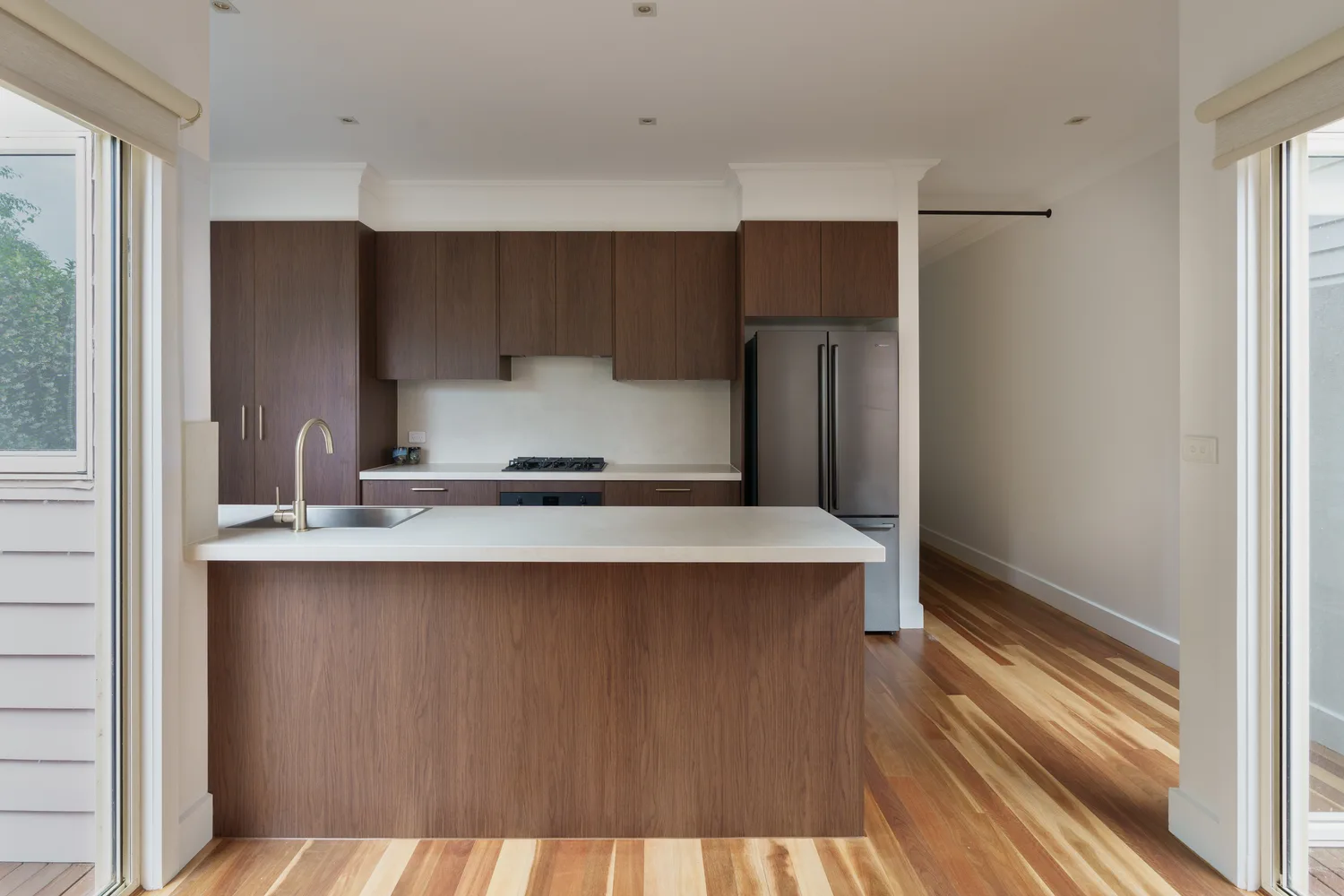 Renovated kitchen with walnut cabinetry and stone island by MNA Builds