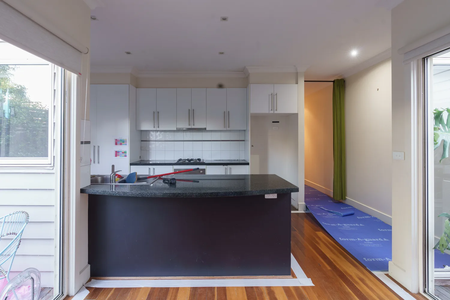 Dated kitchen with white cabinetry and dark laminate island before renovation