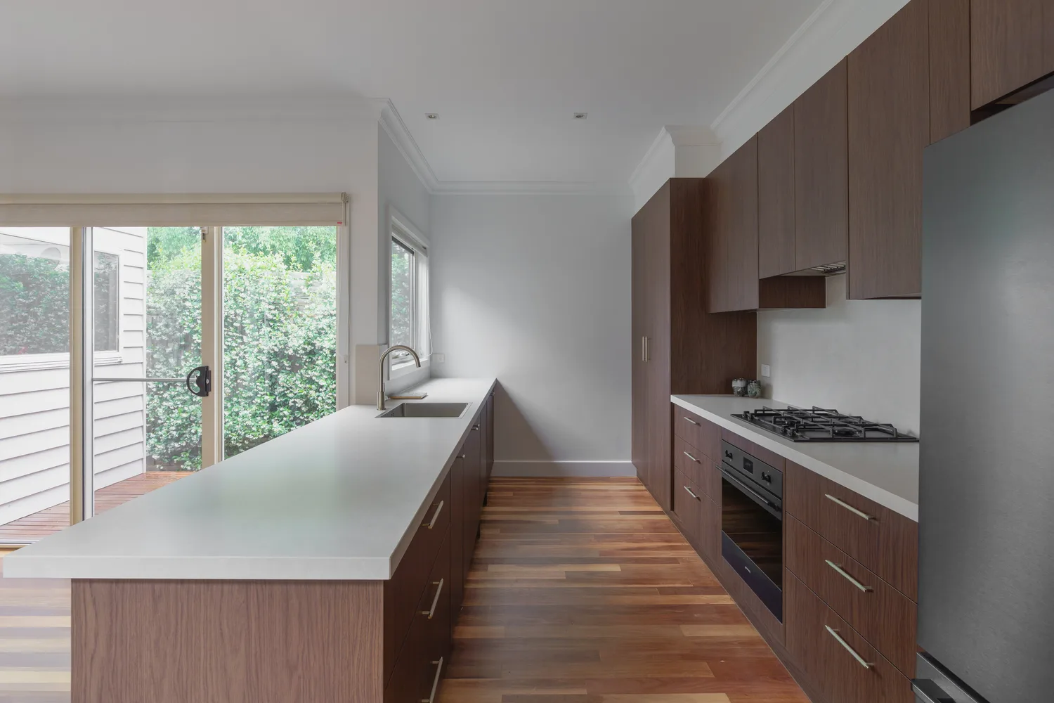 Renovated galley kitchen with timber joinery and stone benchtop by MNA Builds