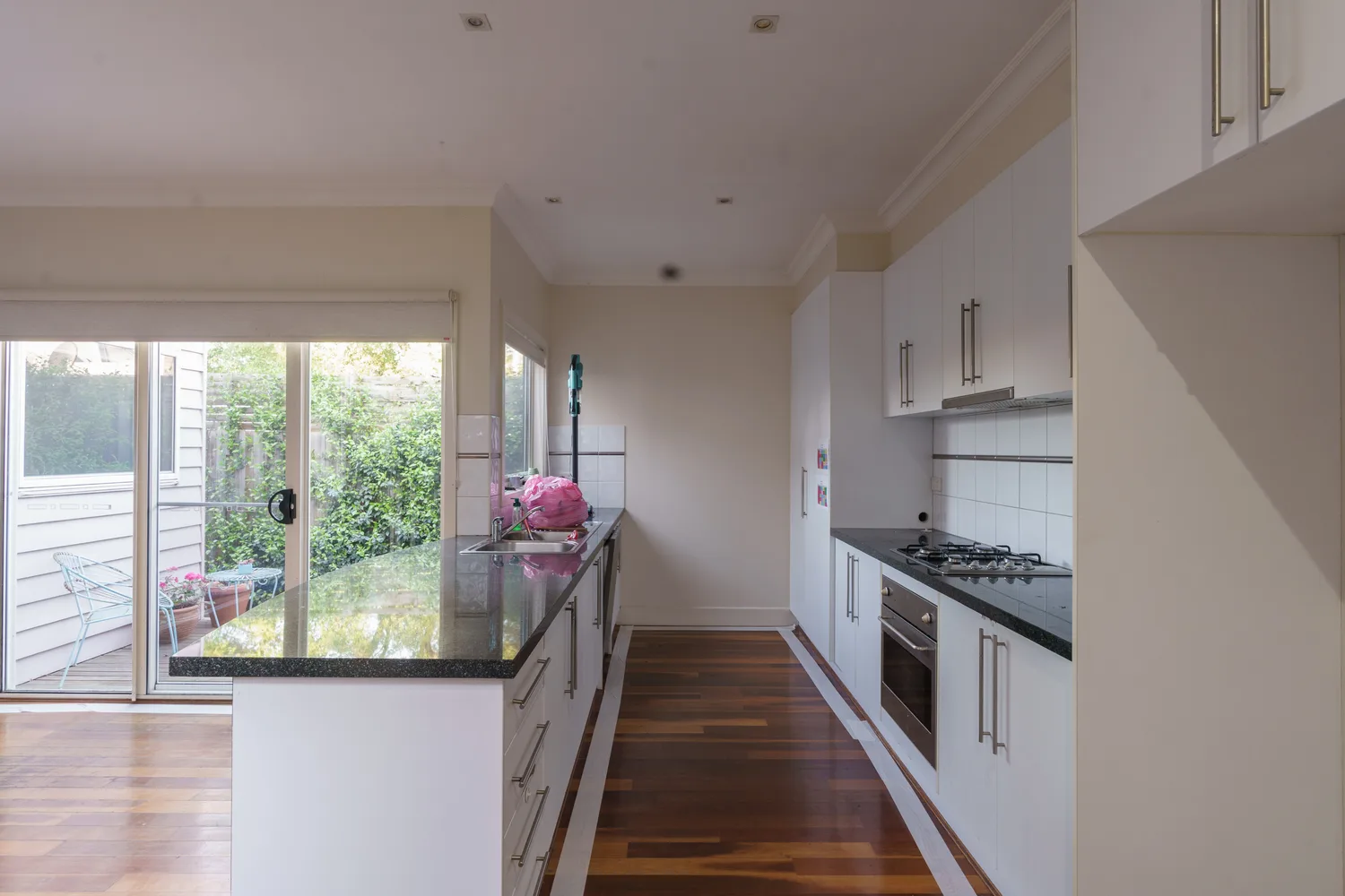 Original galley kitchen with dark benchtop before renovation