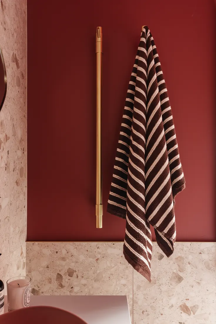 Deep red feature wall with striped towel and brass rail by MNA Builds