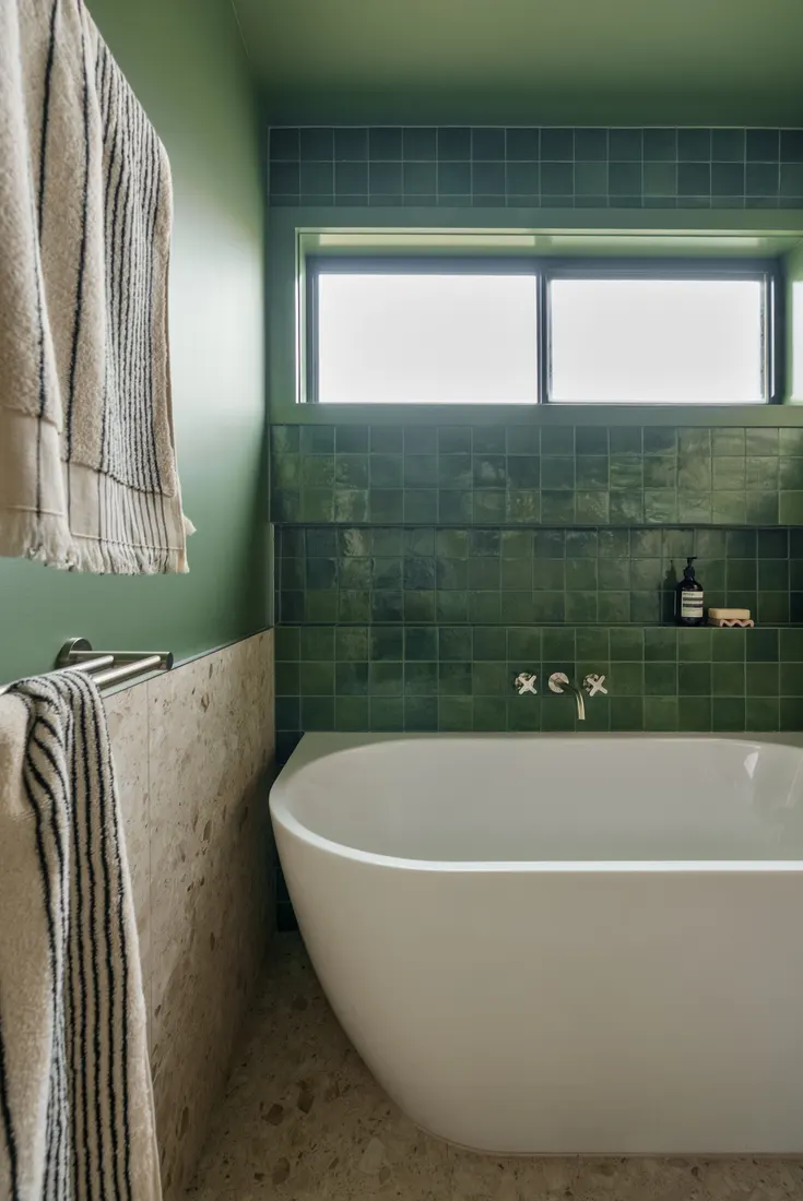 Green zellige tiled wall with round mirror and timber vanity by MNA Builds