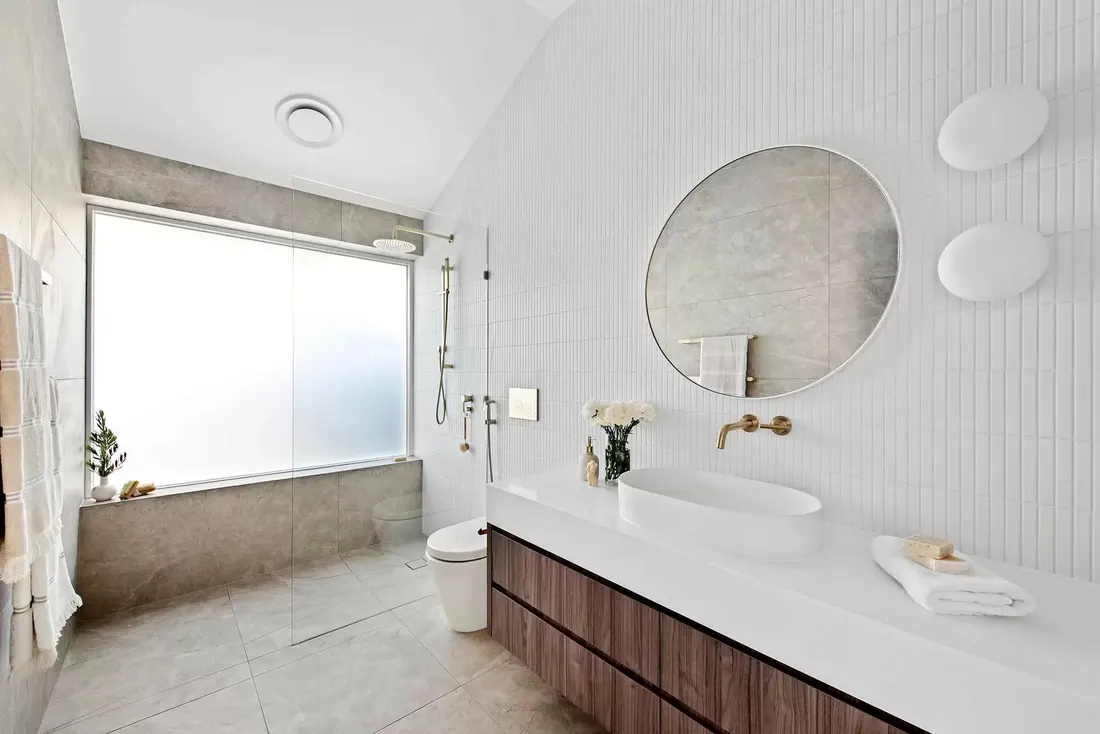 Designer bathroom with timber vanity and round mirror by MNA Builds